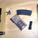 AR-15 upgrades to make your rifle run better – optic, trigger, muzzle brake, magazine follower, and handguard laid out on a workbench